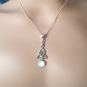 May include: A silver Celtic knot pendant necklace with a white moonstone drop. The pendant is in the shape of a trinity knot, a traditional Celtic symbol of love, faith, and hope.