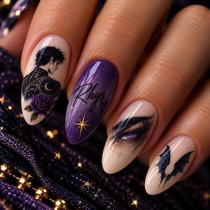 Könnte beinhalten: Mandelformige Fingernägel mit detaillierter Nagelkunst. Ein Nagel zeigt eine männliche Figur mit einer violetten Rose, ein anderer hat ein violettes Glitzer-Finish mit dem Text 'Rhys' und einem Stern, ein dritter zeigt ein violettes Auge und der letzte schwarze Fledermausflügel.