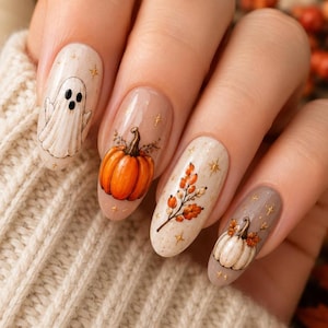Könnte beinhalten: Oval geformte Fingernägel mit herbstlichem Nageldesign. Die Motive zeigen einen weißen Geist, einen leuchtend orangefarbenen Kürbis, einen Zweig mit orangefarbenen Beeren und Blättern sowie einen weißen Kürbis, verziert mit kleinen goldenen Sternen.