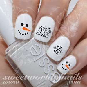 May include: White nail polish with black and orange snowman nail art decals. The decals feature a snowman with a carrot nose, black eyes, and black buttons. Other decals include a snowflake and the text "Let it Snow".