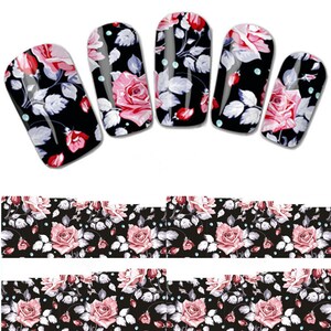 May include: Black nail wraps with a floral rose design. The roses are pink and red with white leaves and accents. The nail wraps are shown on five fingernails and in strips.