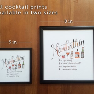 May include: Two framed Manhattan cocktail prints, 5 x 5 inches and 8 x 8 inches, with a handwritten recipe and illustrations of ingredients. The larger print is 8 inches (20 cm) square.