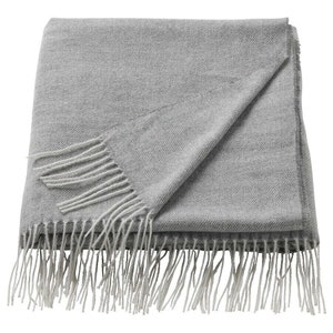 May include: A gray throw blanket with a white fringe. The blanket is folded in half and the fringe is visible on both sides.