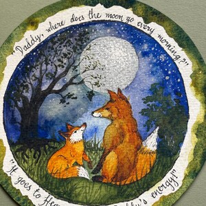 Könnte beinhalten: Eine kreisförmige Aquarellillustration mit zwei orangefarbenen Füchsen auf einer nächtlichen Wiese unter einem großen silbernen Mond und einem dunkelblauen Sternenhimmel. Der Text lautet: "Daddy, where does the moon go every morning?" und "It goes to Heaven, to visit Daddy's energy!"