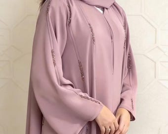Op de afbeelding: Een mauve abaya met lange mouwen en een bijpassende hoofdbedekking. De abaya heeft decoratieve kralen langs de voorkant en mouwen. Het kledingstuk heeft een vloeiend, elegant ontwerp.