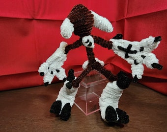 May include: A brown and white pipe cleaner toy with multiple limbs and a box in the background.