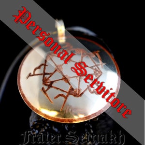 May include: A silver pendant with a brown, intricate design inside a clear, round, glass dome. The pendant is on a black cord and has the text "Personal Service" and "Frater Sernakh" written in red.