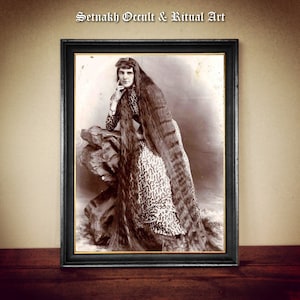 May include: Sepia-toned framed photograph of a woman with exceptionally long hair, wearing a patterned dress and seated on a rock. The image has the text "Setnakh Occult & Ritual Art" at the top, and is in a black frame.