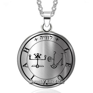 May include: A silver-colored pendant necklace with a circular pendant. The pendant features intricate black symbols and text within a circular border. The necklace chain is also silver. The text "Setnakh Ritual Art" is at the bottom of the pendant.