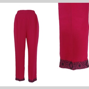 Può includere: Un paio di pantaloni rosa fucsia con un bordo geometrico bianco e nero nella parte inferiore delle gambe.