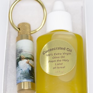 Peut inclure: Un coffret cadeau contenant une bouteille d'huile d'olive consacrée et un petit flacon avec un porte-clés doré. La bouteille d'huile a un bouchon blanc et une étiquette dorée qui dit "Consecrated Oil 100% Extra Virgin Olive Oil From the Holy Land of Isreal 05 fl oz."