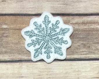 May include: A white felt snowflake applique with a blue glitter design.