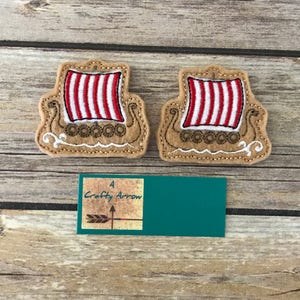 May include: Two felt appliques of Viking ships with red and white striped sails. The ships are brown and have white details.