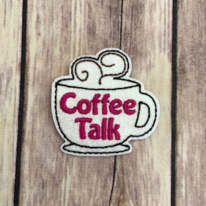 Puede incluir: Taza de café blanca con un diseño rosa "Coffee Talk" y vapor marrón saliendo de la parte superior.