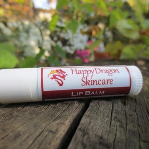May include: White tube of Happy Dragon Skincare lip balm with a red dragon logo and the words "Happy Dragon Skincare" and "Lip Balm" printed on the label.