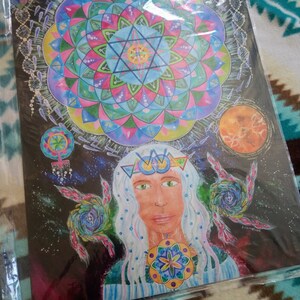 May include: A colorful mandala with a geometric design, surrounded by stars and a woman with long white hair wearing a crown. The woman has green eyes and a serene expression. The background is black with a hint of purple.