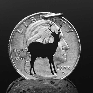 Könnte beinhalten: Eine silberne US-Viertel-Dollar-Münze mit einer ausgeschnittenen Silhouette eines Hirsches in der Mitte. Die Münze trägt die Inschriften "Liberty", "In God We Trust" und "2023".