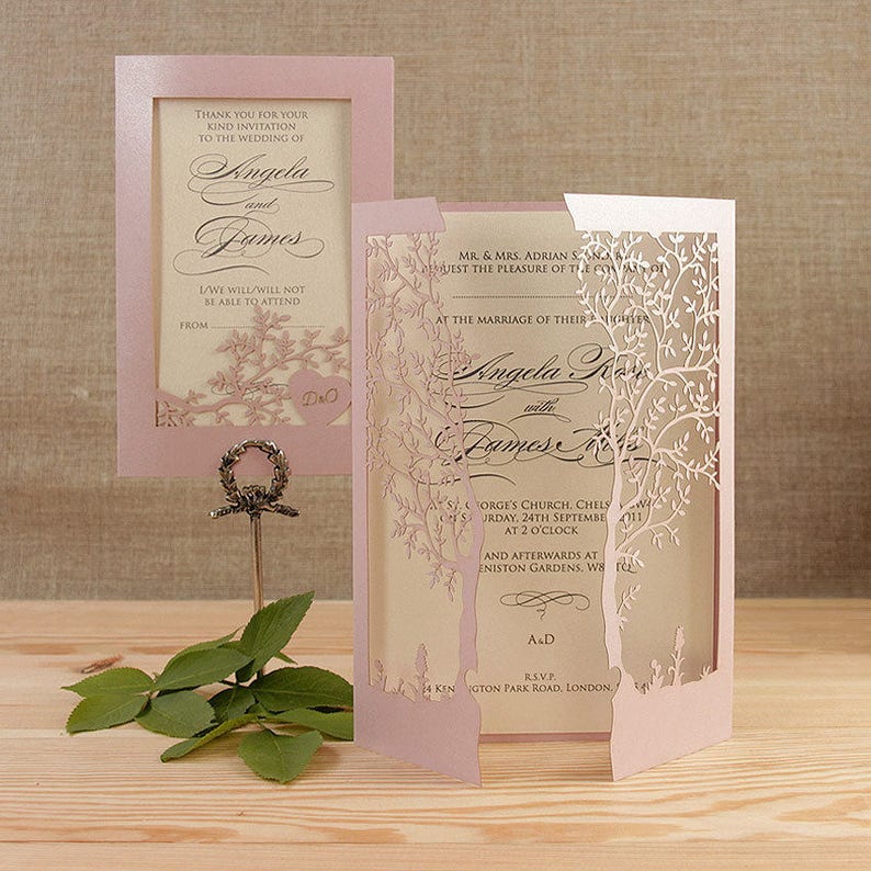 May include: A pink and white wedding invitation with a laser cut design of trees. The invitation reads "At the marriage of their children Angela and James".