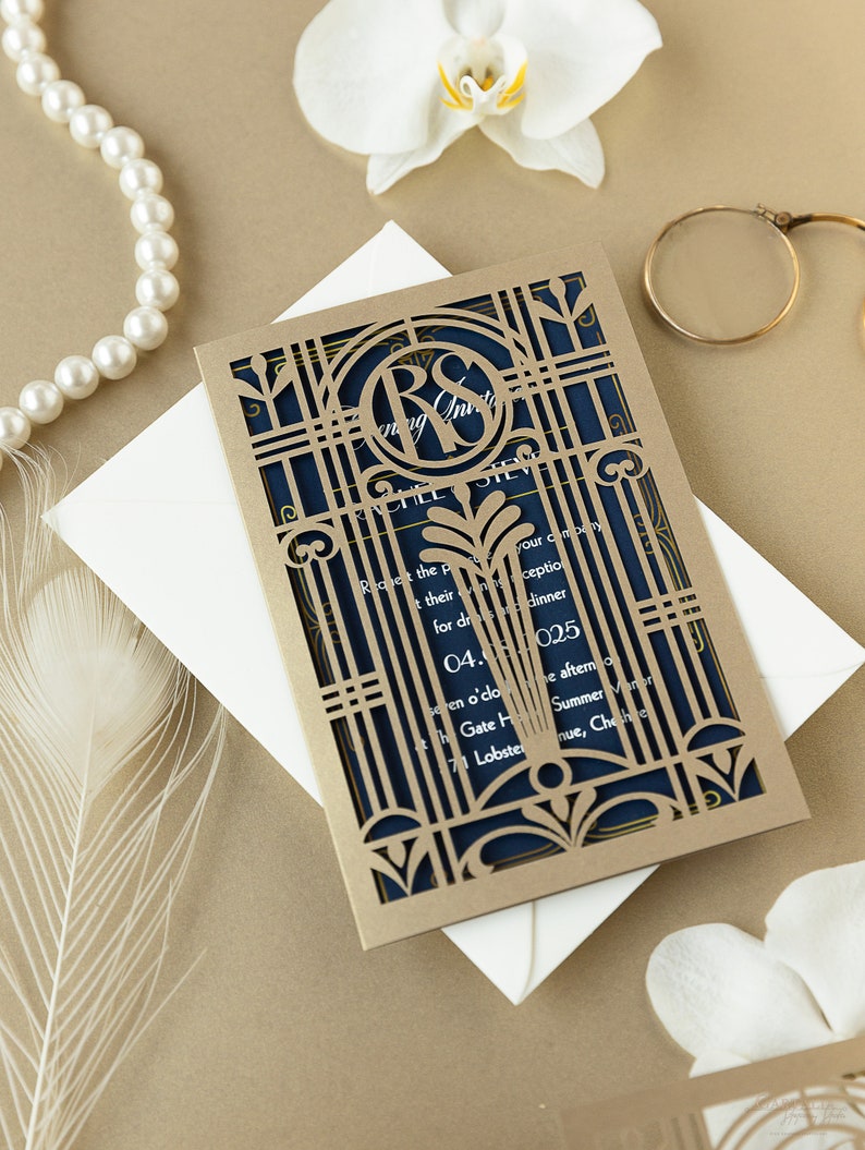 May include: Gold laser cut wedding invitation with a navy blue inner layer. The invitation features a monogram of the letters "R" and "S" in a decorative frame. The text on the invitation reads "Request the pleasure of your company for dinner" and includes the date, time, and location of the wedding.
