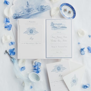 Puede incluir: Un conjunto de invitaciones de boda azul y blanco con una ilustración de acuarela de un edificio y un diseño floral. La invitación incluye los nombres de la pareja, la fecha y la hora de la boda, y la ubicación. La tarjeta RSVP también está incluida.