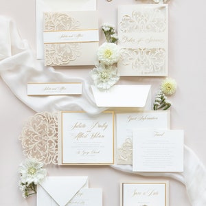 May include: Wedding invitation suite with laser cut ivory cardstock featuring a floral design with gold accents. The invitation includes the names Juliette Daily and Allert Wilson, the date September 17th, 2023, and the location St. George Church.
