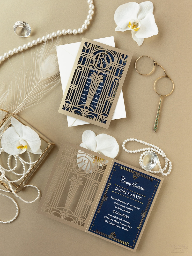 May include: A gold and navy blue wedding invitation with a laser cut design. The invitation features a monogram of the couple's initials, "R" and "S", and the text "Evening Invitation Rachel & Steven" in gold lettering. The invitation is set on a gold background with white flowers and pearls.