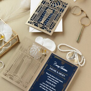 May include: A gold and navy blue wedding invitation with a laser cut design. The invitation features a gate design with a monogram of the couple's initials. The text on the invitation reads "Evening Invitation Rachel & Steven Request the pleasure of your company at their evening reception for drinks and dinner 04.08.2025 seven o'clock in the evening at The Gate House, Summer Manor 871 Lobster Avenue, Chelsea"
