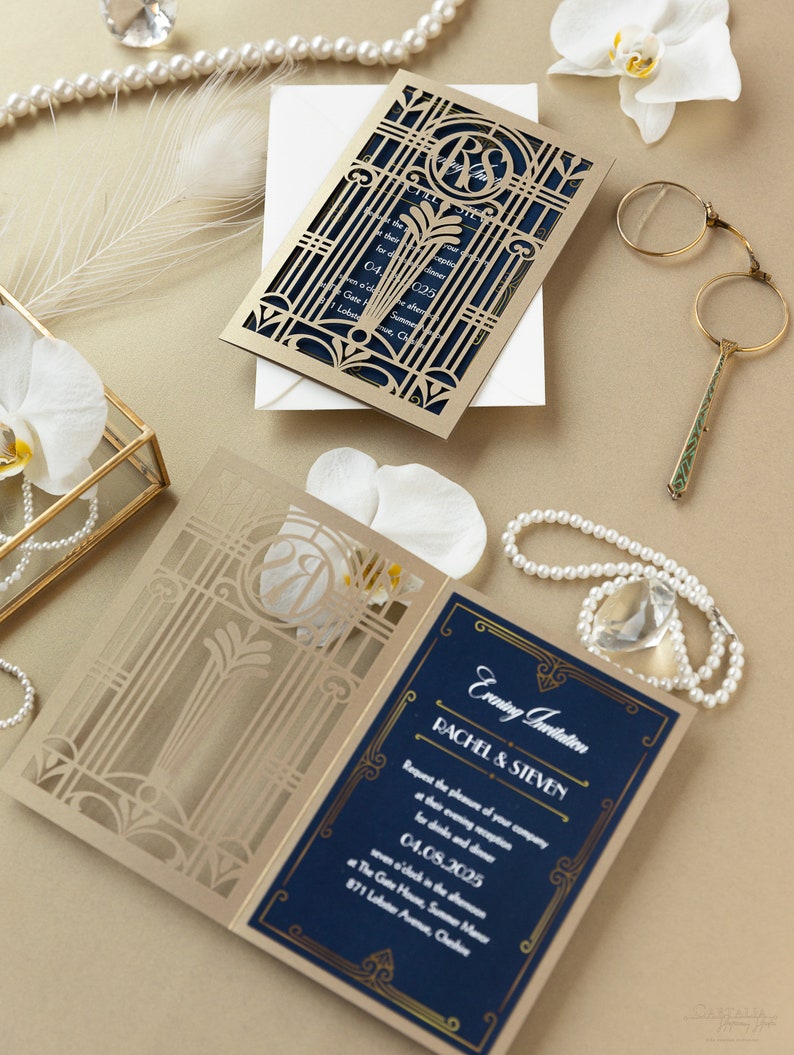 May include: A gold and navy blue wedding invitation with a laser cut design. The invitation features a gate design with a monogram of the couple's initials. The text on the invitation reads "Evening Invitation Rachel & Steven Request the pleasure of your company at their evening reception for drinks and dinner 04.08.2025 seven o'clock in the evening at The Gate House, Summer Manor 871 Lobster Avenue, Chelsea"