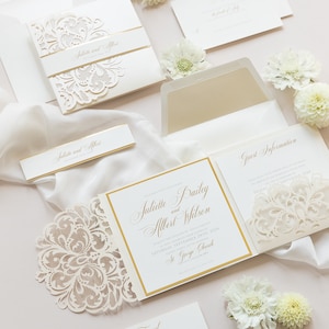 May include: A white wedding invitation suite with gold accents and a delicate lace design. The invitation features the names "Juliette Bailey and Albert Wilson" and the date "Saturday, September 24th, 2024". The invitation also includes the location "St. George Church".