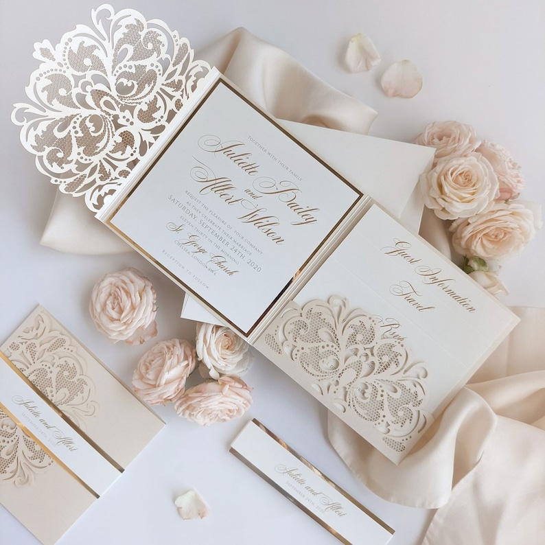 May include: A white and gold wedding invitation with a laser-cut design. The invitation features the names "Juliette Bailey" and "Albert Wilson" and the date "Saturday, September 24th, 2020".