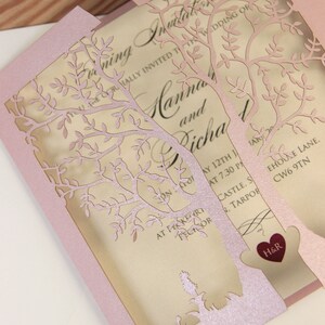 May include: A pink laser cut wedding invitation with a tree design. The invitation features the text "Wedding of Hannah and Richard" and the date "May 12th at 7:30 PM".