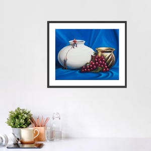May include: A framed art print featuring a still life with a white vase, a golden vase, and a bunch of red grapes. Two miniature figures appear to be working on the white vase. The background is a blue fabric.