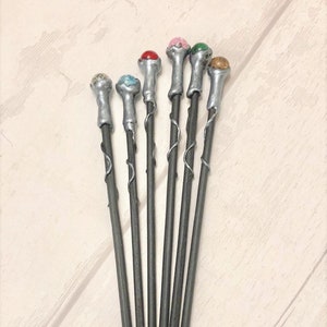 May include: Set of eight silver wands with different colored gemstone tips. The wands are about 10 inches long and have a twisted design.