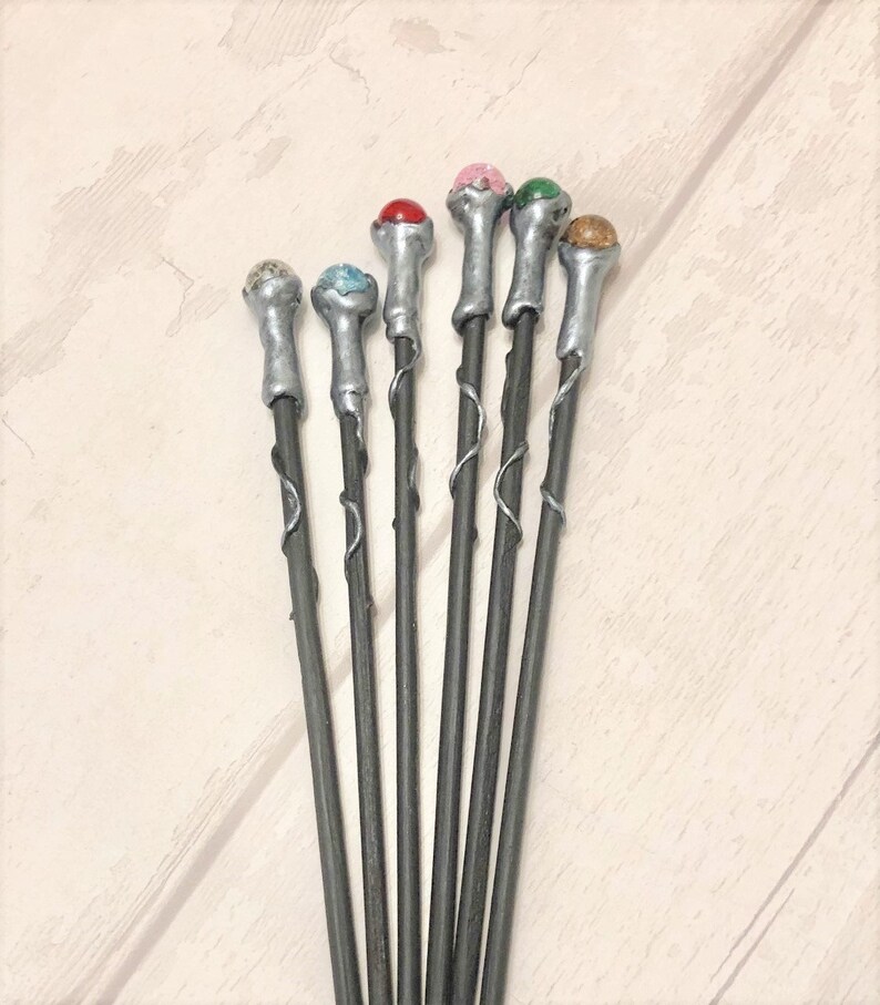 May include: Set of eight silver wands with different colored gemstone tips. The wands are about 10 inches long and have a twisted design.