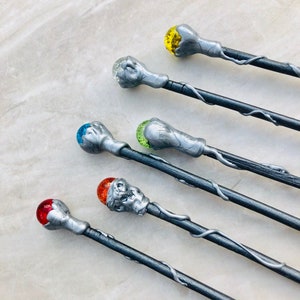 May include: Six silver wands with different colored glass orbs on the ends. The orbs are red, orange, yellow, green, blue, and clear.