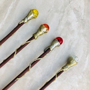 May include: Four wooden wands with different colored glass orbs on the ends. The orbs are yellow, orange, red, and clear.