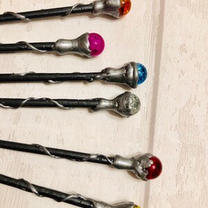May include: Five black wands with silver tips and colorful glass orbs. The orbs are orange, pink, blue, clear, and red.