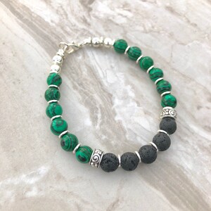 Può includere: Un braccialetto di perline verdi e nere con accenti argentati. Il braccialetto è realizzato con perline di malachite e pietra lavica.