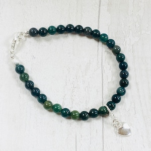 May include: A green agate beaded bracelet with a silver heart charm. The bracelet is made with small, round beads and has a silver clasp.