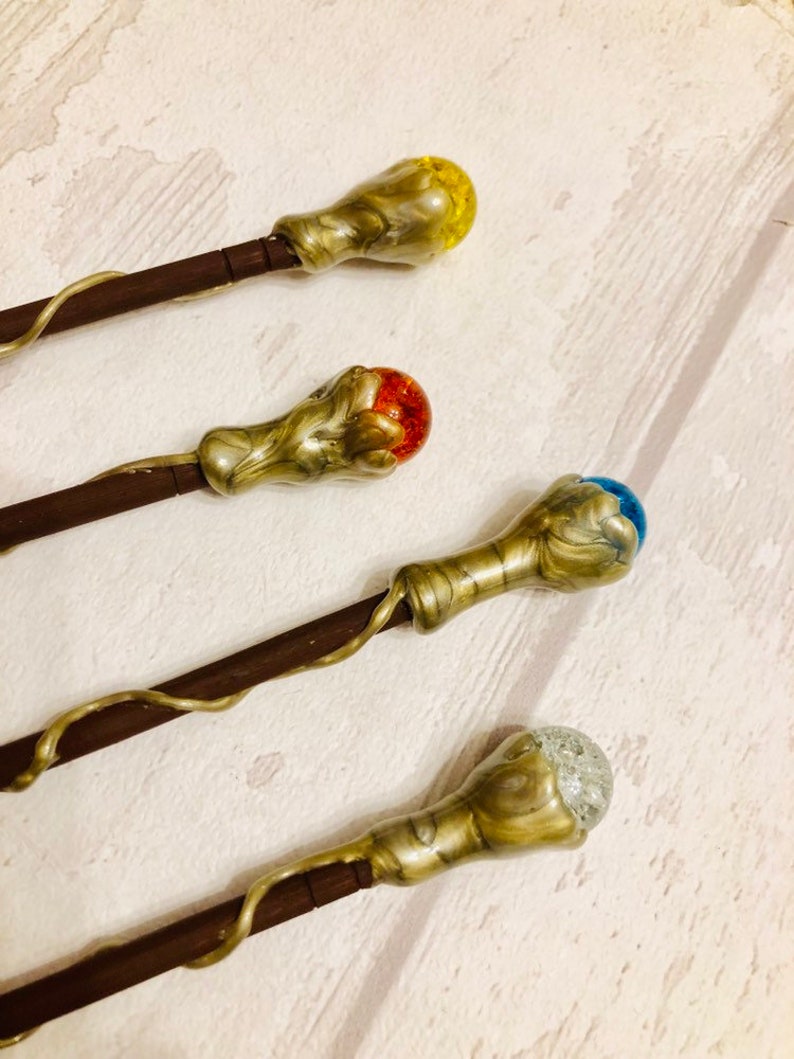 May include: Four decorative wands with different colored glass orbs on the ends. The wands are made of wood and have a gold-colored finish. The orbs are yellow, red, blue, and clear with glitter.