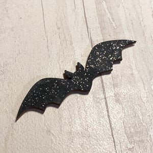 May include: Black glitter bat cutout, a Halloween decoration.