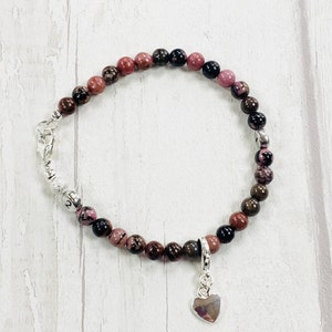 May include: A pink, brown, and black beaded bracelet with a silver heart charm.