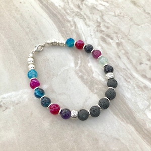 May include: A beaded bracelet with black lava rock beads, silver beads, and colourful agate beads. The bracelet has a silver clasp.