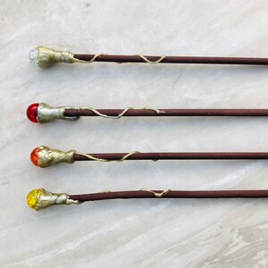 May include: Four wooden wands with different colored glass tips. The tips are clear, red, orange, and yellow.
