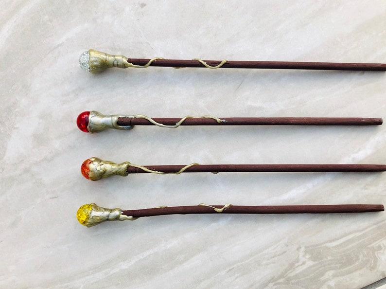 May include: Four wooden wands with different colored glass tips. The tips are clear, red, orange, and yellow.