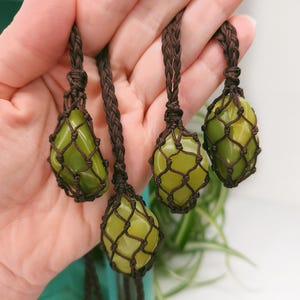 May include: Three green jade stone pendants in brown macrame string holders. The stones are smooth and polished and have a light green color.