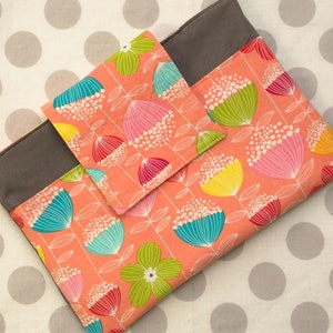 Puede incluir: Una funda para port&aacute;til de tela gris y melocot&oacute;n con un patr&oacute;n floral. La funda tiene un bolsillo m&aacute;s peque&ntilde;o en la parte delantera.