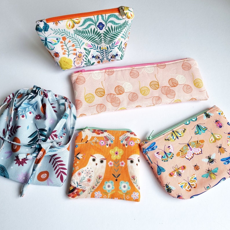 May include: Five different fabric pouches with various patterns. The pouches are made of cotton fabric and have a zipper closure. The patterns include floral, geometric, and abstract designs. The pouches are in various colors, including pink, blue, green, and orange.