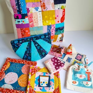 May include: A collection of colorful fabric patchwork items, including a pillow, a pouch, and several small bags. The items are all made with different patterns and colors of fabric, and they are arranged on a white surface.