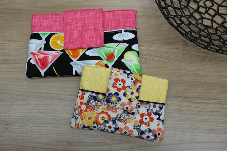 Puede incluir: Dos bolsas de tela con diferentes patrones. La primera bolsa es negra con una solapa rosa y un estampado de c&oacute;cteles coloridos. La segunda bolsa es amarilla con un estampado floral blanco y negro.